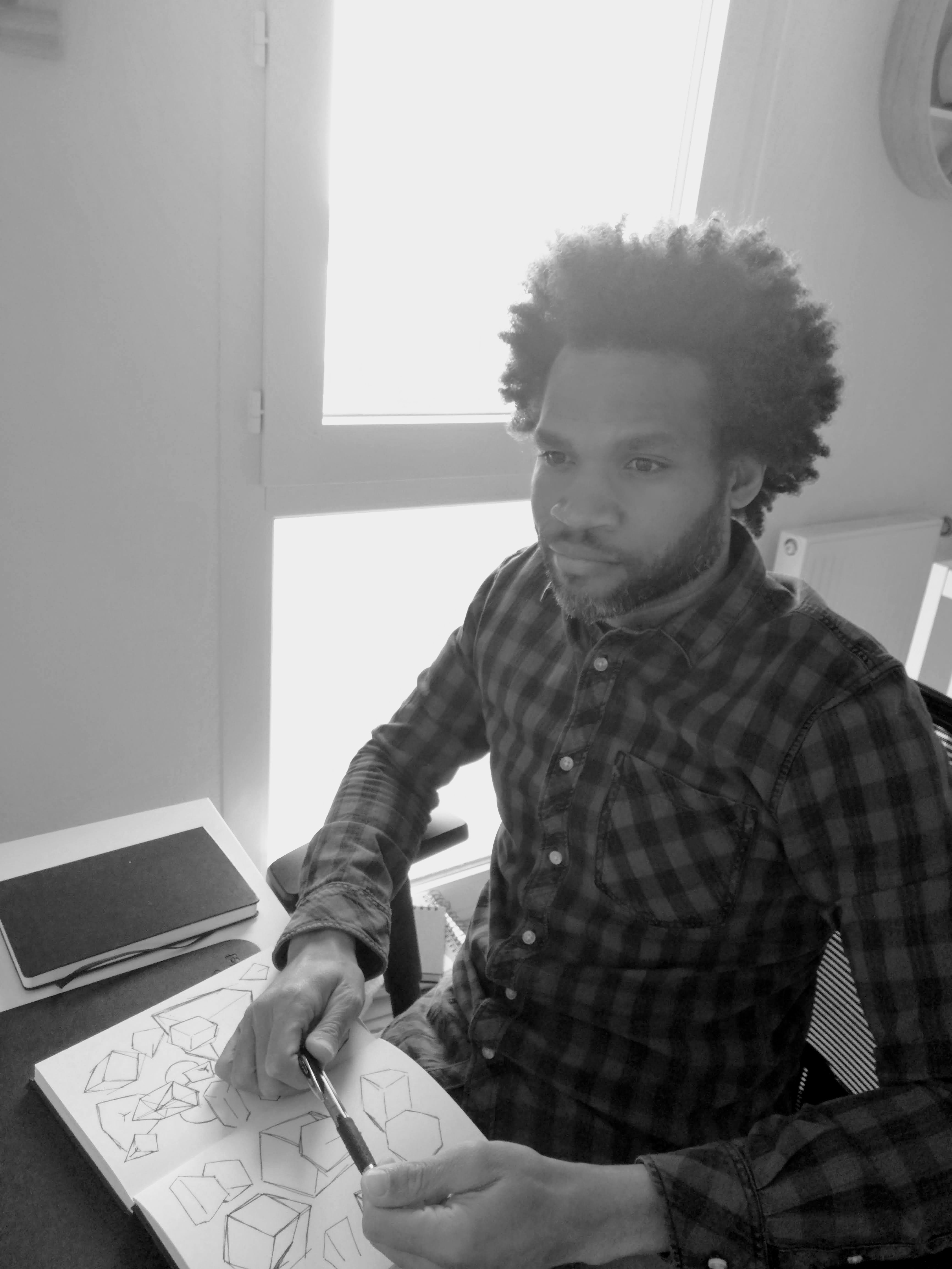 Raynald dessinant à son bureau.